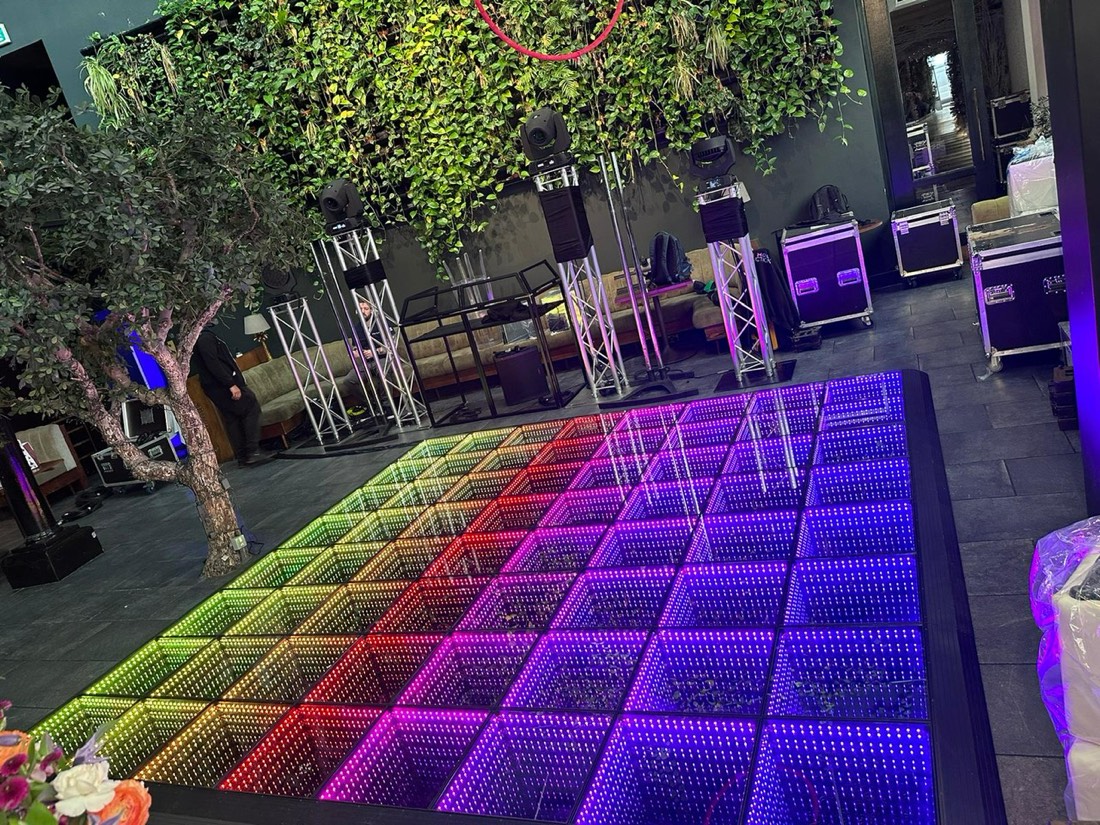 Rainbow infinity LED dance floor beside a living plant wall