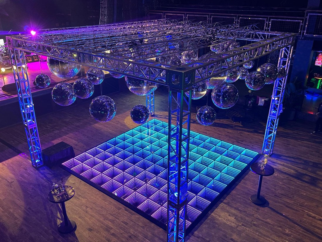 Mirror ball rig suspended over a blue and violet infinity LED dance floor