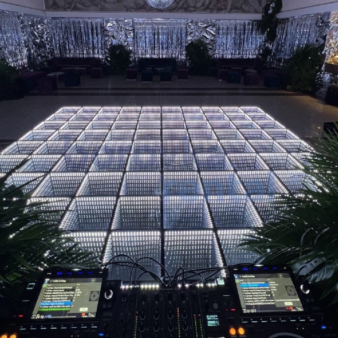 All-white infinity LED dance floor transforming a silver-draped reception hall